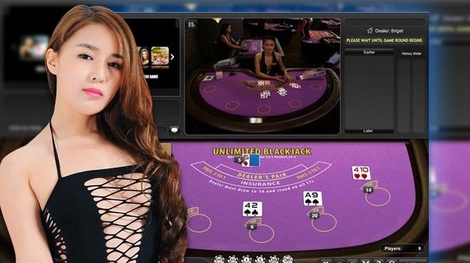 Рыжеволосая азиатка в черном платье-сетке позирует на фоне игрового стола для лайв-блэкджека