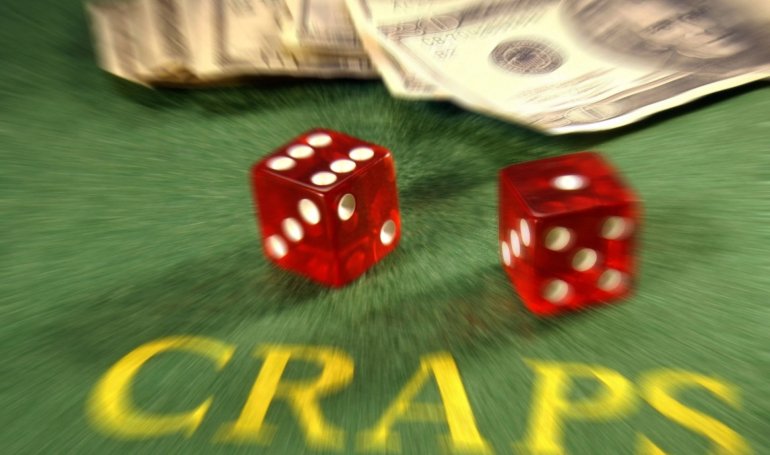 Два красных кубика для игры в кости лежат на зеленом игорном поле с надписью "Craps"