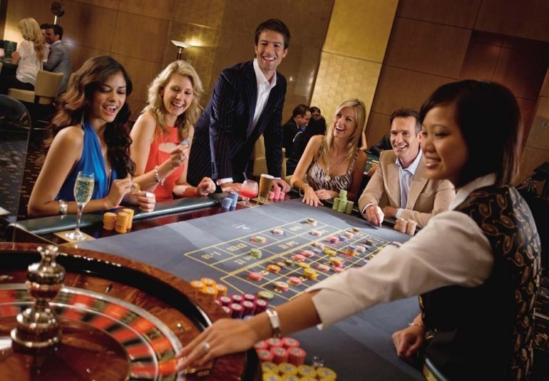 Девушки в коктейльных платьях и парни в строгих костюмах играют в рулетку в казино