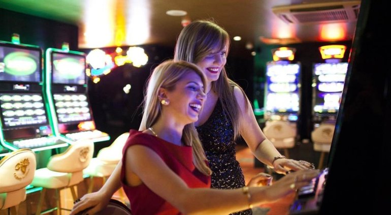 Две блондинки развлекаются игрой на автоматах в казино