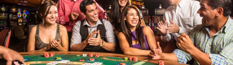 Два молодых мужчины и две девушки красотки сидят за игорным столом для покера