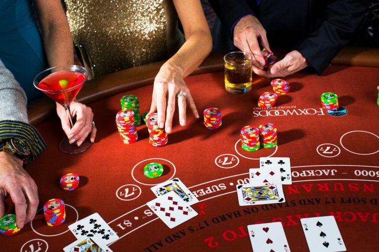 Вид сверху на стол для игры в покер, за которым люди распивают коктейли и совершают ставки