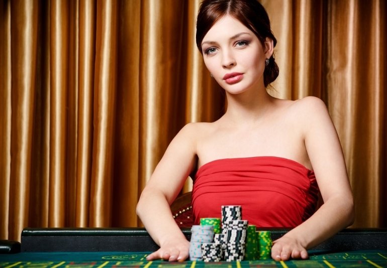 Красотка в красном платье позирует за игорным столом в казино
