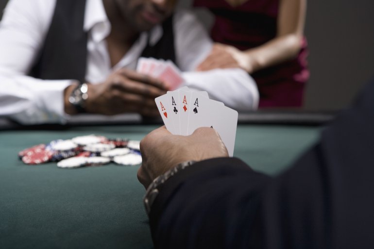 Противники сидят за столом для покера и смотрят каждый в свои карті