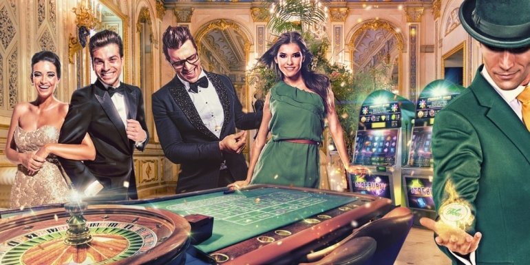 Красиво одетые молодые люди в компании девушек в вечерних нарядах играют в рулетку в роскошном казино